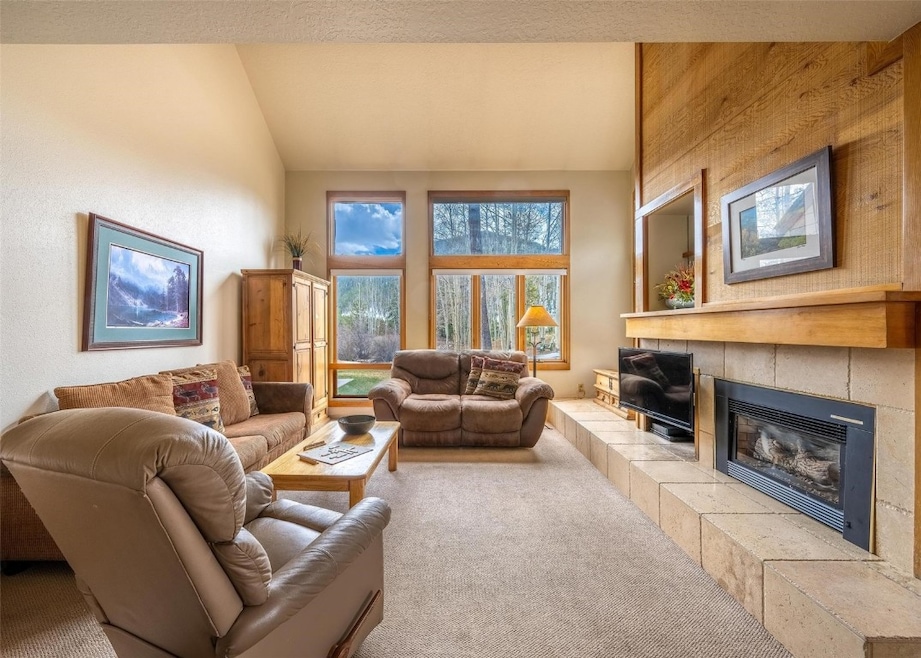 Carpeted living area with a tile fireplace and lof