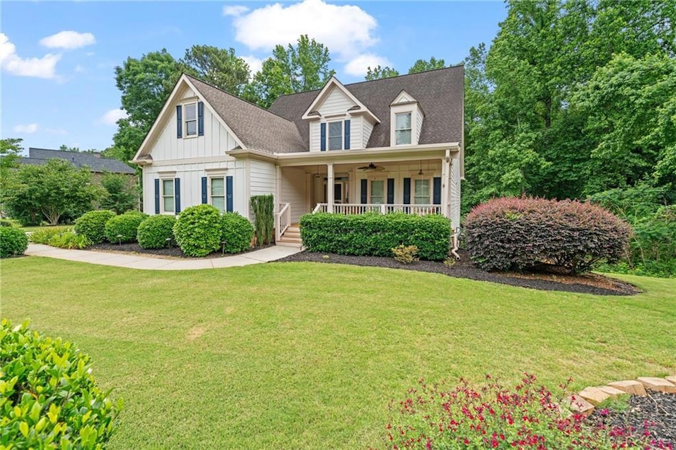 View of front of property with ceiling fan, covered porch, a front yard, board and batten siding, and a shingled roof