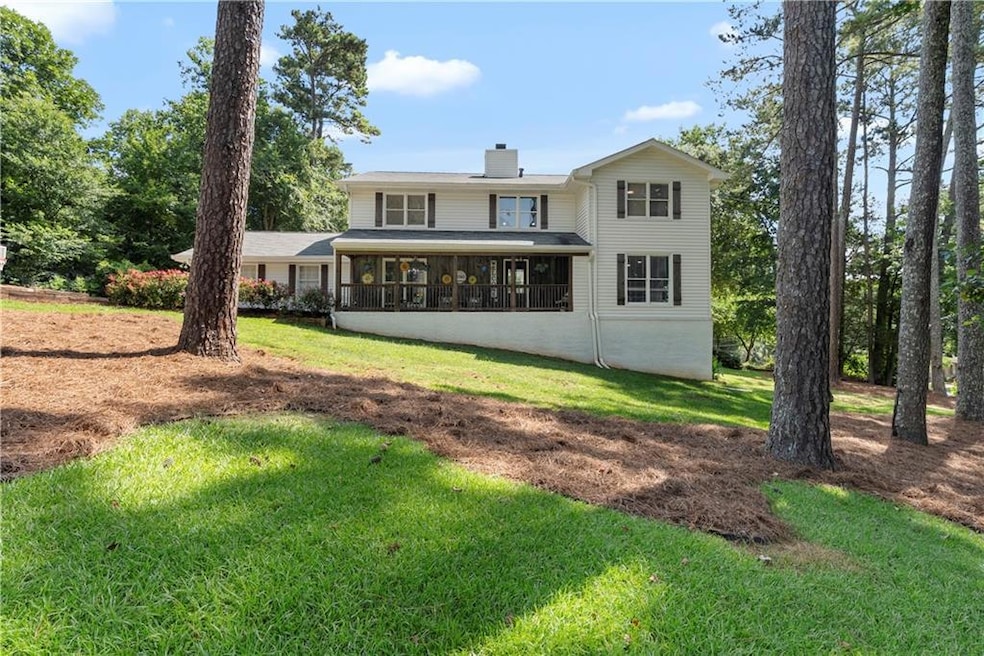 Rear view of property with a chimney and a lawn