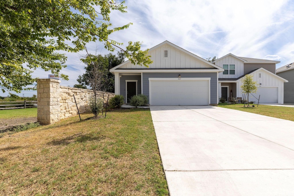 View of front of property with board and batten siding, concrete driveway, and an attached garage