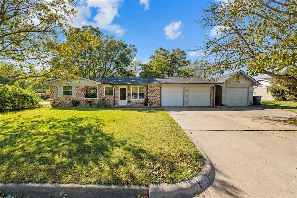 Ranch-style home with a front yard, concrete driveway, an attached garage, and brick siding