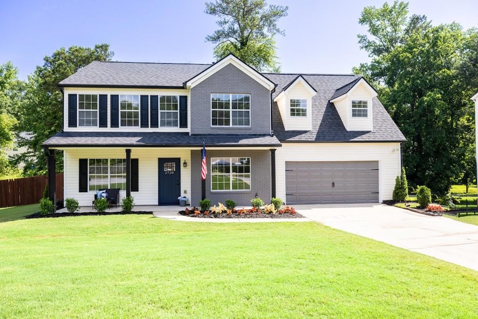 View of front facade featuring concrete driveway, a porch, an attached garage, and a shingled roof