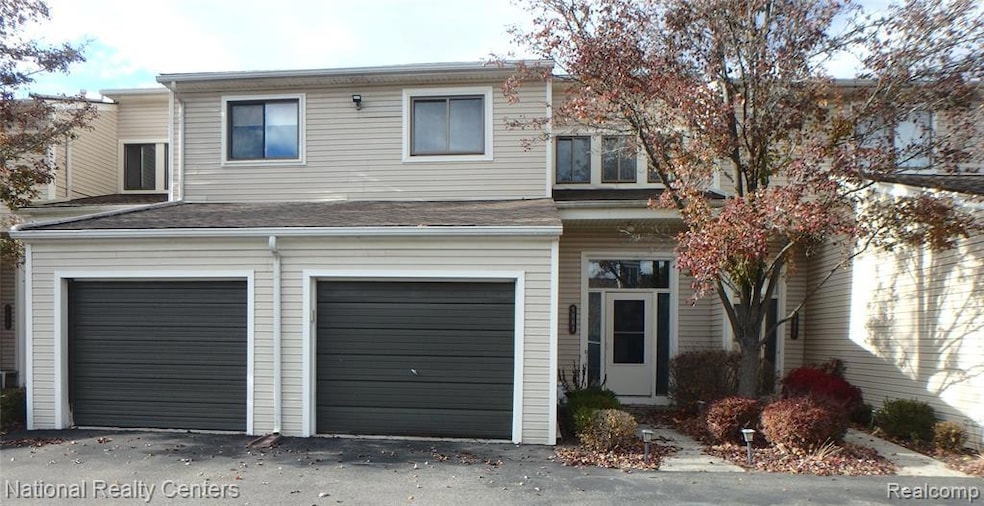 Traditional home featuring an attached garage, driveway, and a shingled roof