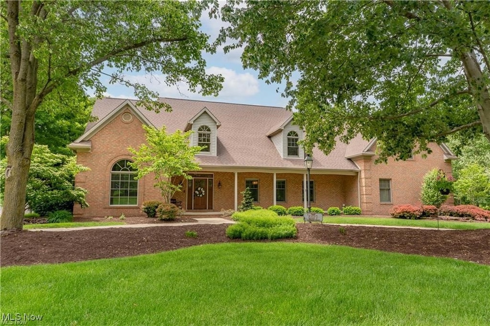 Cape cod house with covered porch, a front yard, brick siding, and a shingled roof