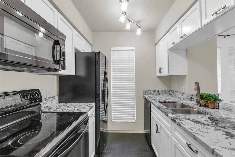 Kitchen with a sink, white cabinets, black applian