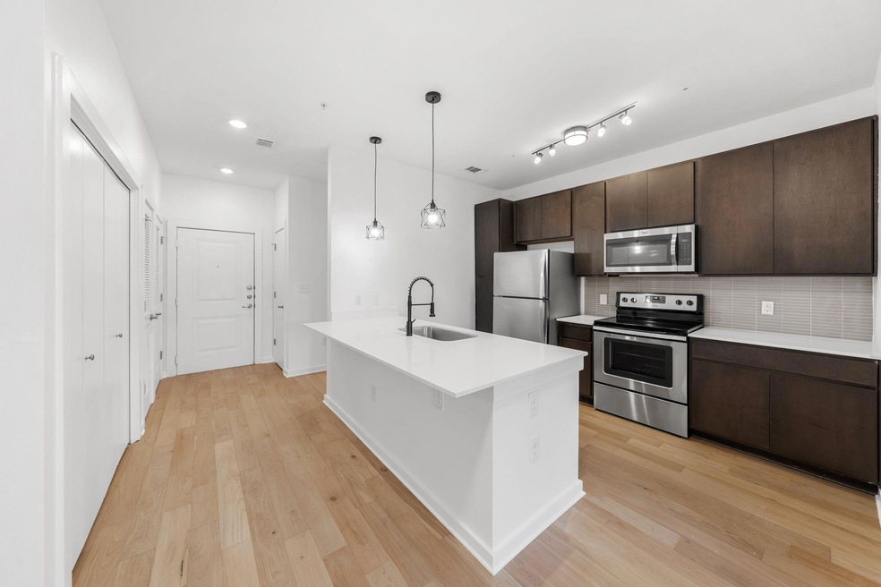Kitchen with light wood finished floors, dark brown cabinets, appliances with stainless steel finishes, and a sink