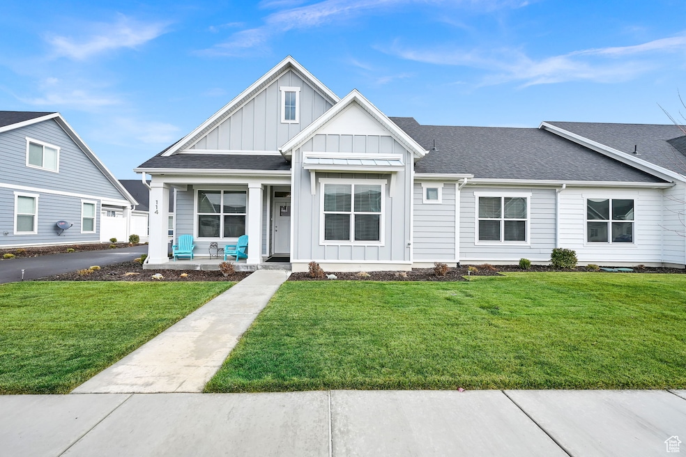 View of front of house with board and batten siding, roof with shingles, covered porch, and a front yard