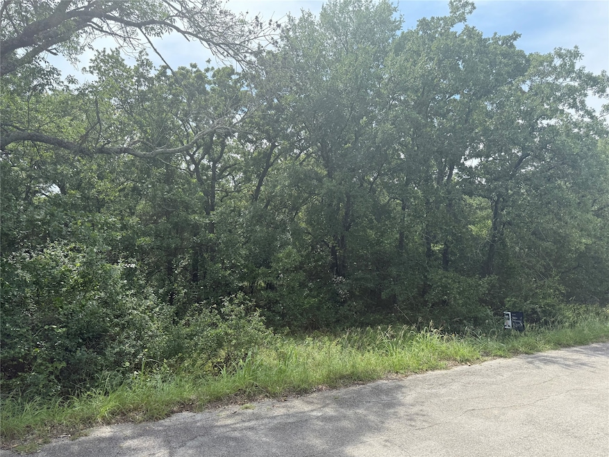 View of asphalt road featuring a wooded view