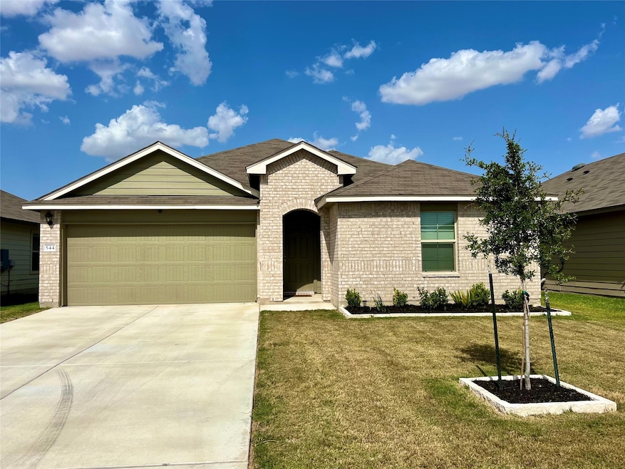 Ranch-style home featuring concrete driveway, a front yard, a garage, brick siding, and a shingled roof