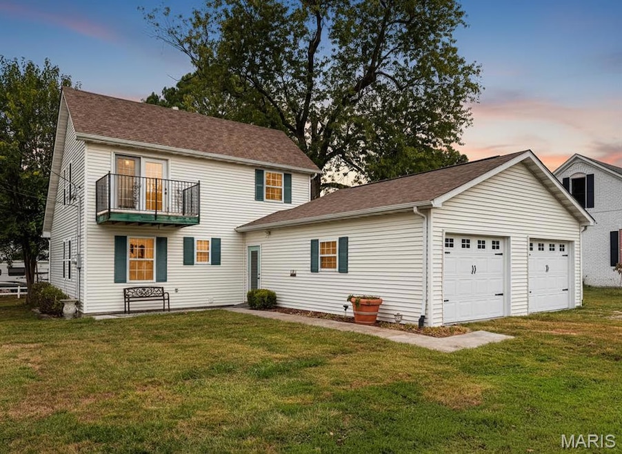 Digitally Staged View of front of property with a garage, a lawn, a balcony, and roof with shingles