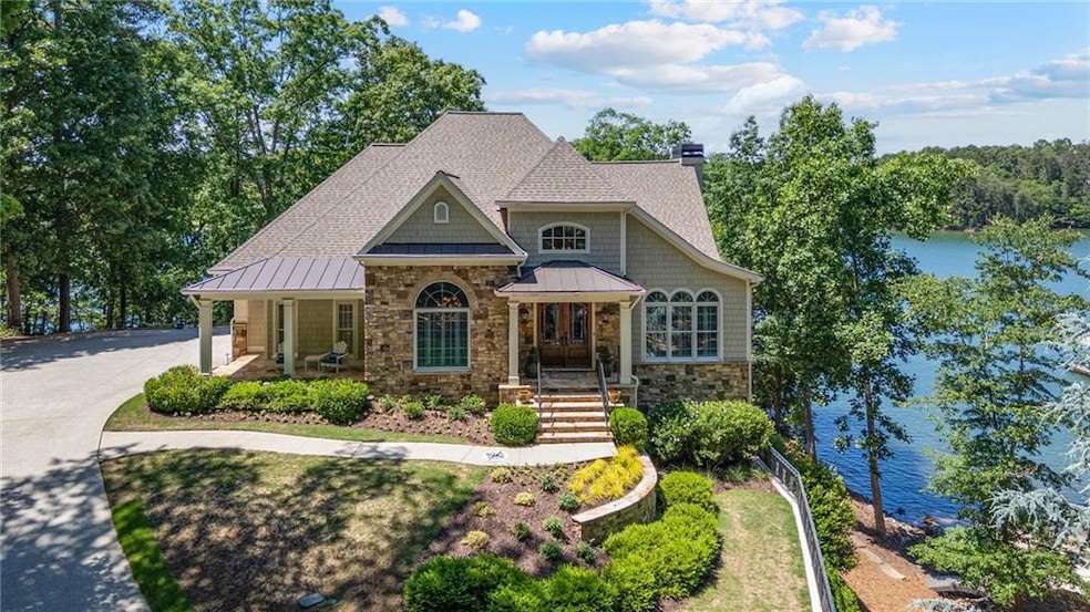 Craftsman inspired home featuring a standing seam roof, stone siding, a chimney, and a water view