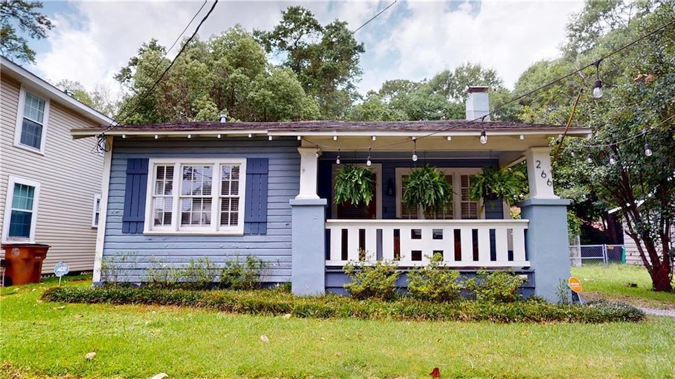 View of front facade featuring covered porch, a chimney, and a front yard