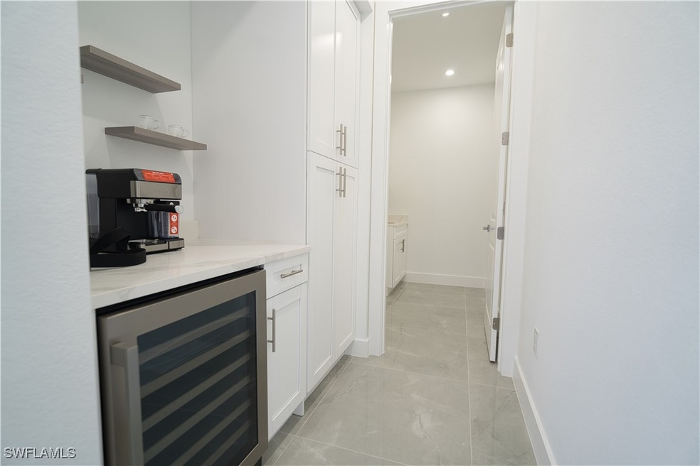 Indoor dry bar featuring wine cooler, light marble