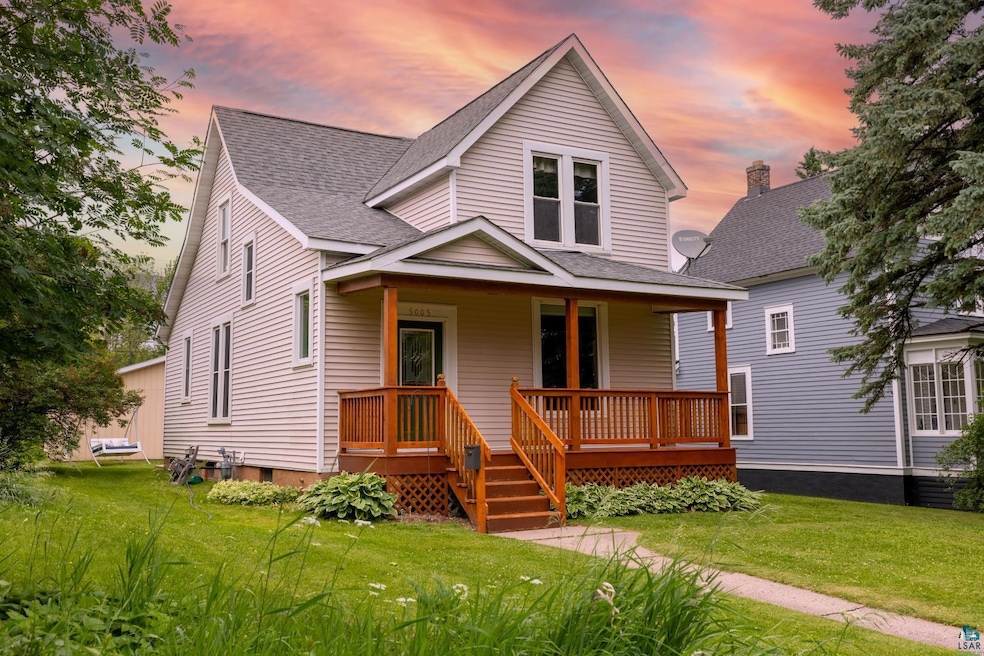 View of front of home featuring a lawn, covered porch, and roof with shingles
