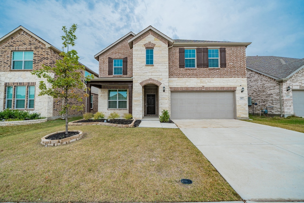 View of front facade featuring stone siding, brick siding, driveway, and a front lawn