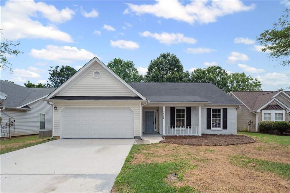 Ranch-style house featuring a porch, an attached garage, concrete driveway, and a front lawn