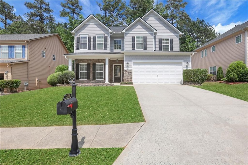 View of front of home featuring concrete driveway, a garage, a front yard, and stone siding