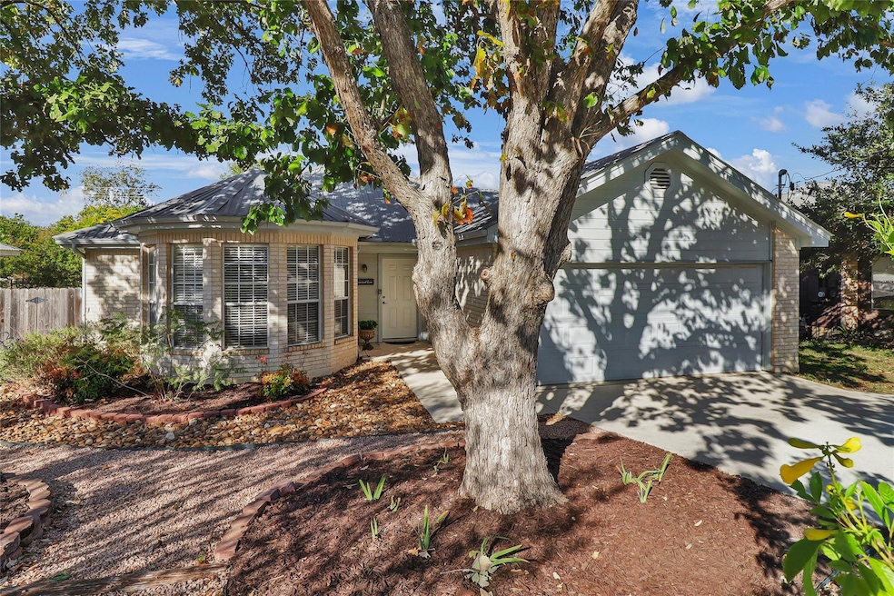 View of front facade with brick siding, driveway, and a garage