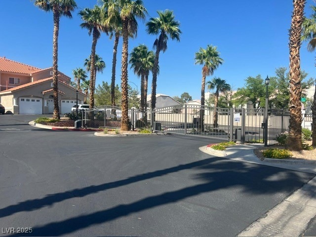 View of asphalt road featuring a gate, curbs, and