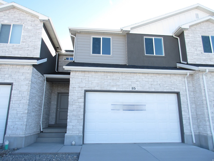View of front of home with stone siding, a garage, and driveway