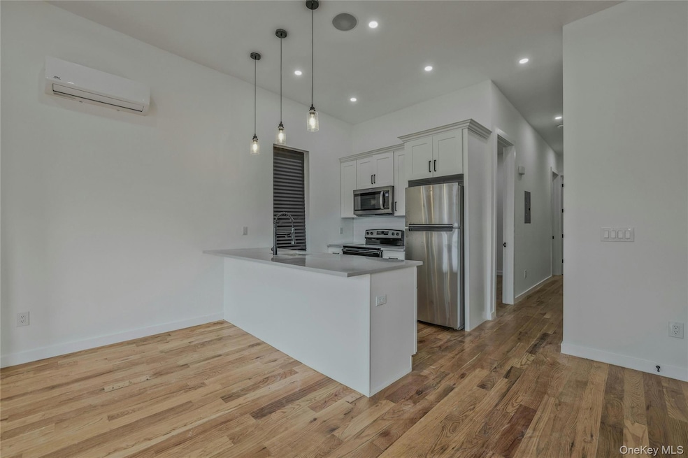 Kitchen with white cabinets, stainless steel appliances, pendant lighting, recessed lighting, and a peninsula