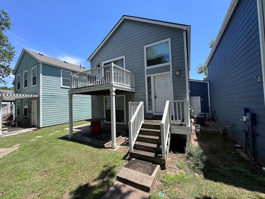 Back of house with a lawn and a balcony