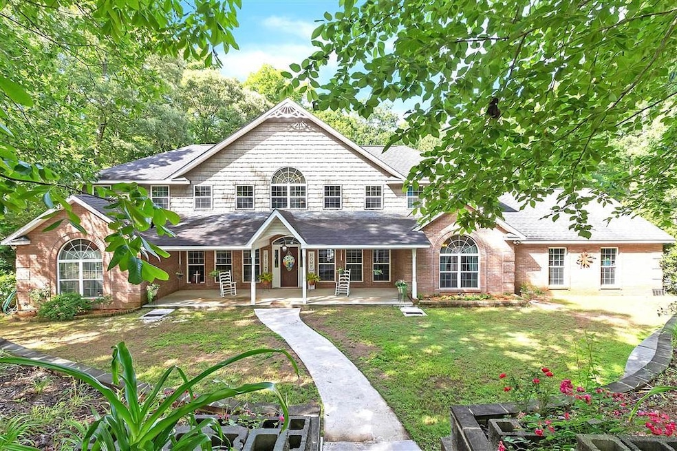 Back of house with a yard, covered porch, brick si