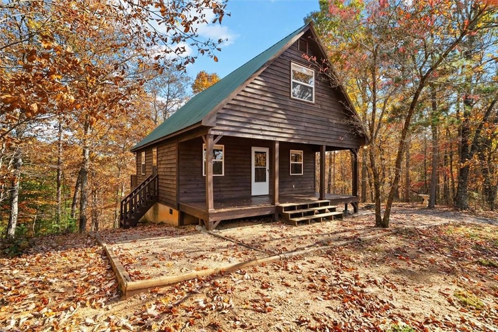 Chalet / cabin featuring a porch, a metal roof, and a view of trees