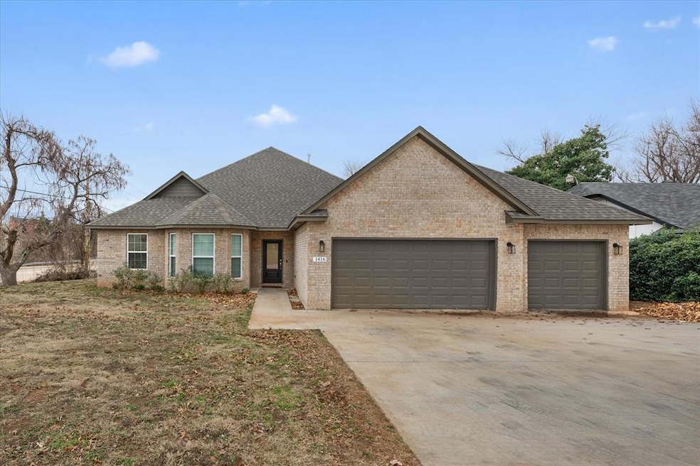 View of front of property with an attached garage, roof with shingles, and brick siding