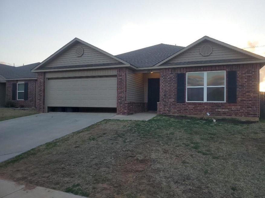 Ranch-style home with a garage, a front yard, bric