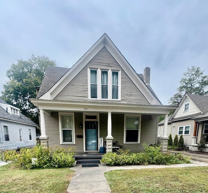 View of front of house with a front yard, a chimney, and covered porch