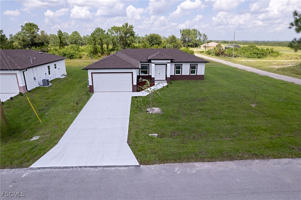 Ranch-style house featuring concrete driveway, an attached garage, roof with shingles, a front yard, and stucco siding
