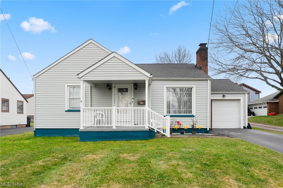 View of front of property featuring a front yard, a garage, and covered porch