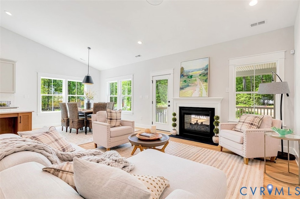 Living room featuring recessed lighting, a multi sided fireplace, lofted ceiling, and light wood finished floors