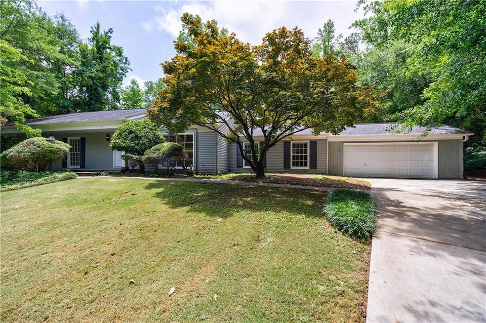 View of front facade with concrete driveway, an attached garage, and a front lawn