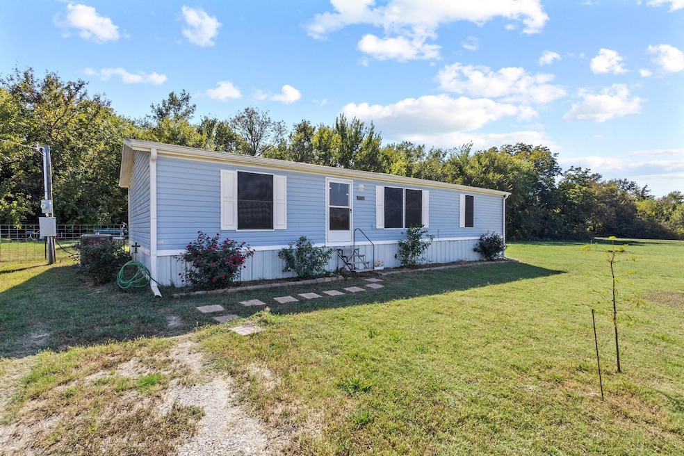 Manufactured / mobile home featuring a front yard and view of scattered trees