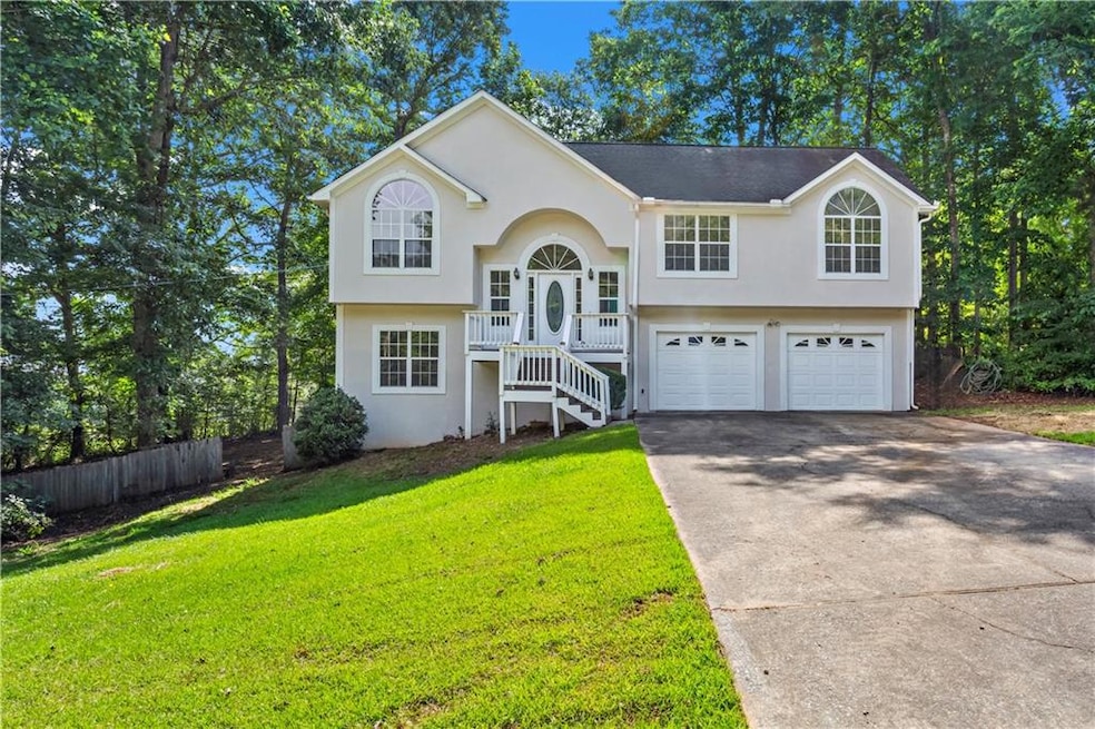 Split foyer home featuring concrete driveway, stairs, an attached garage, and stucco siding