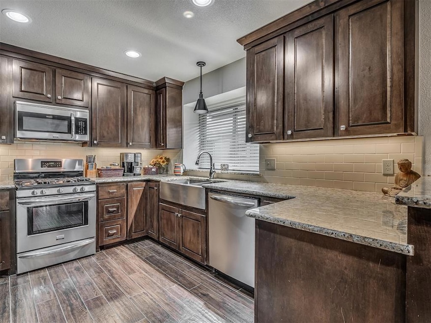 Kitchen featuring stainless steel appliances, dark brown cabinets, dark wood finished floors, backsplash, and recessed lighting