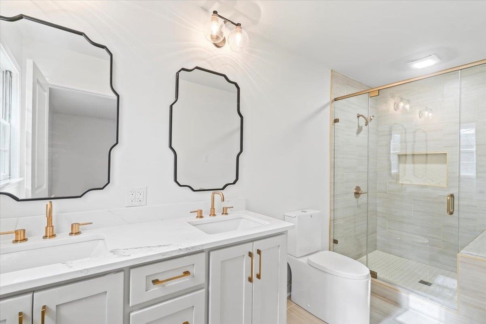 Bathroom featuring vanity, toilet, and a shower wi