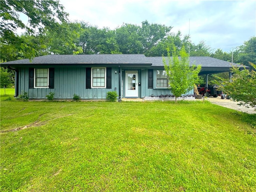 Ranch-style home with board and batten siding, an attached carport, and a front lawn