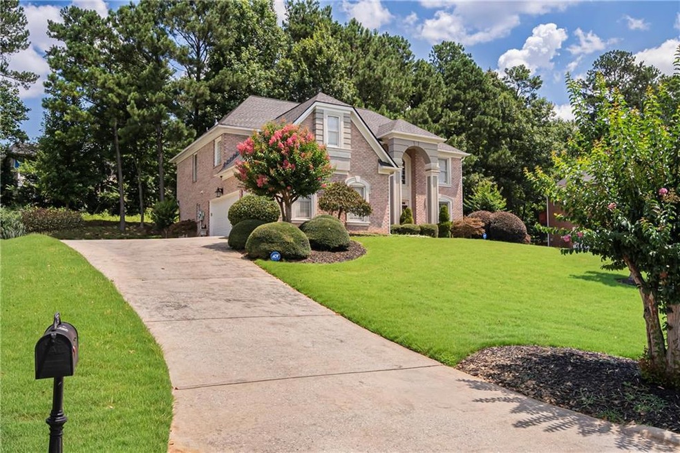 View of front facade featuring brick siding, concrete driveway, a front yard, roof with shingles, and an attached garage