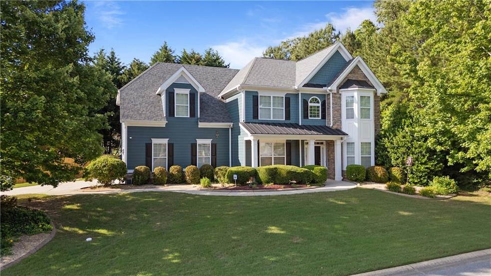 View of front of house featuring a front yard, stone siding, and roof with shingles