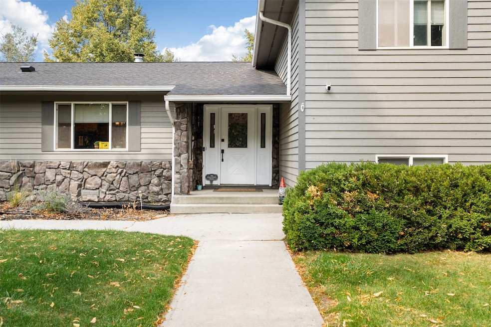 Entrance to property with roof with shingles, a yard, and stone siding
