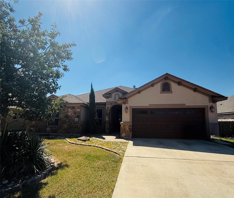 Ranch-style home featuring stone siding, a front lawn, concrete driveway, a garage, and stucco siding