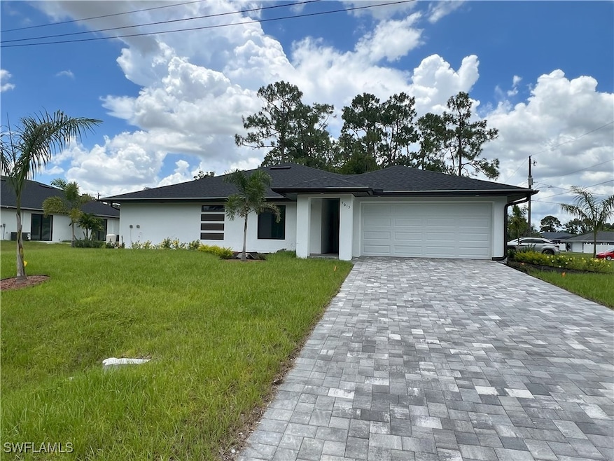 Single story home featuring decorative driveway, an attached garage, stucco siding, and a front yard
