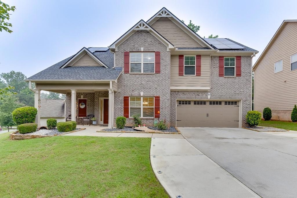 Craftsman house featuring brick siding, a front yard, and solar panels