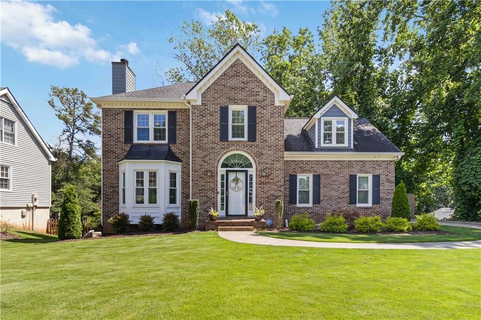 View of front of house featuring a chimney, a front yard, and brick siding