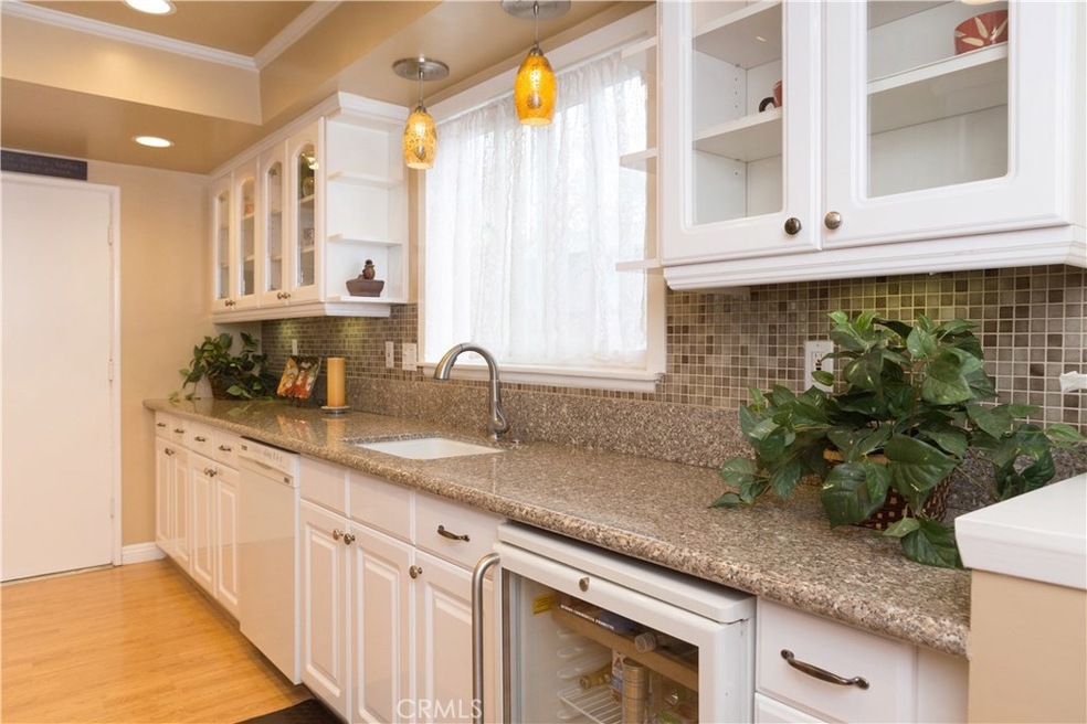 Granite counters and custom backsplash, with bright white glass front cabinets give the perfect finishing touches to this fully updated kitchen which features a commercial grade wine fridge.