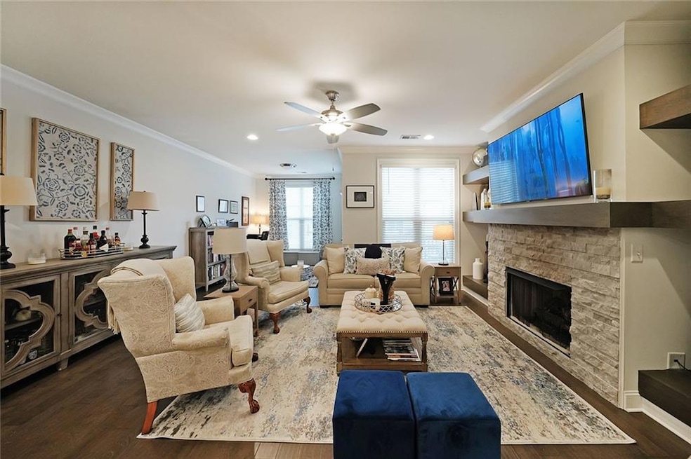 Living room featuring crown molding, ceiling fan, a fireplace, and dark hardwood / wood-style flooring