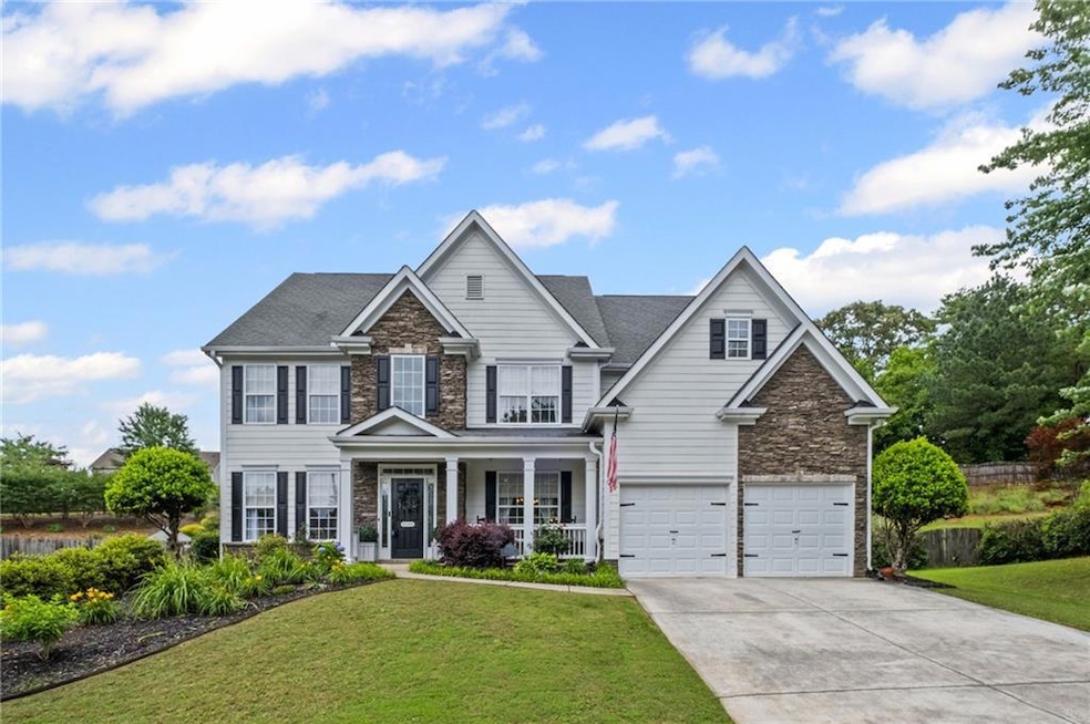 View of front of home with stone siding, a garage, concrete driveway, and a front lawn